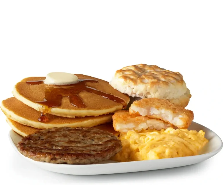 A hearty breakfast with scrambled eggs, sausage, hash browns, a biscuit, and fluffy hotcakes served with syrup.