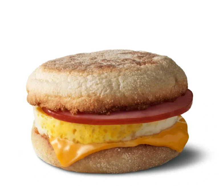 A freshly cracked egg, Canadian bacon, and melted cheese on a toasted English muffin.