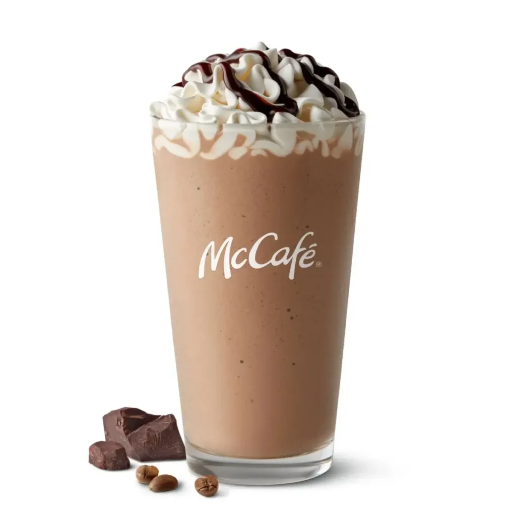 A McCafé® Mocha Frappé, a blended ice drink with chocolate and coffee flavors, topped with whipped cream and chocolate drizzle.