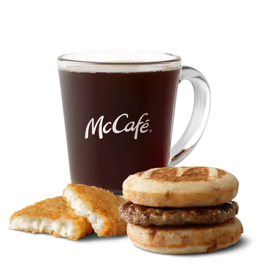 Sweet maple-flavored griddle cakes with sausage, served with hash browns and a drink for a filling breakfast.