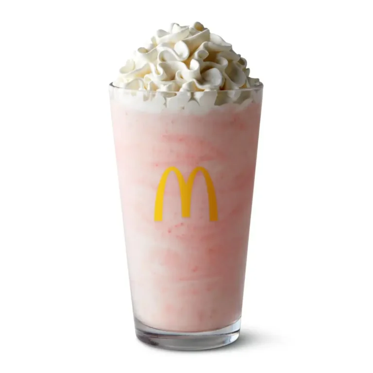 A McDonald's Strawberry Shake made with creamy soft-serve ice cream and sweet strawberry syrup, topped with whipped cream.